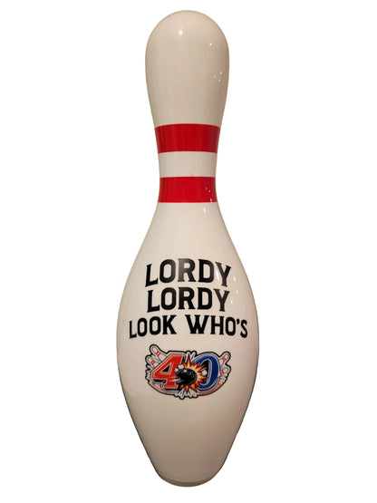 A white bowling pin with red stripes near the top and the text 'LORDY LORDY LOOK WHO'S' above a colorful 40th birthday graphic.
