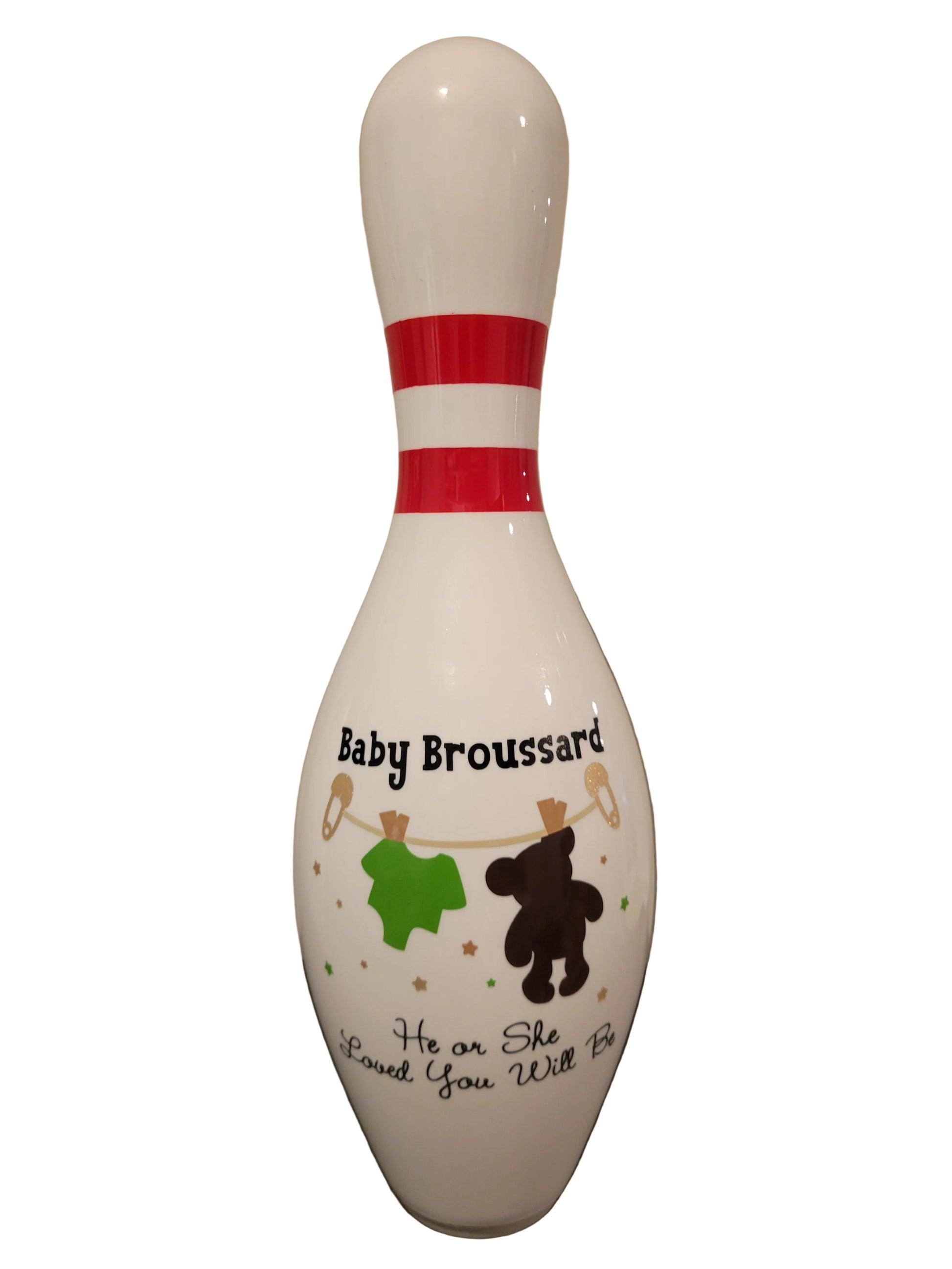 A white baby shower bowling pin with custom printed text reading 'Baby Broussard' and 'He or She Loved You Will Be', decorated with a green shirt, brown teddy bear, and clothesline details.